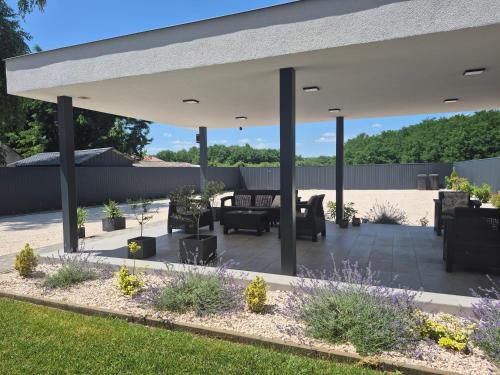 acovered patio with a couch and chairs under a pavilion at Kriszta Deluxe Vendégház in Újfehértó