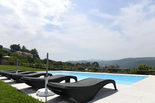 a row of black chairs next to a swimming pool at Vizinhos do Sol Turismo Rural in Valadares
