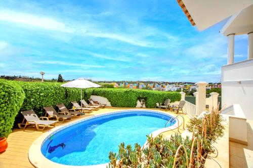a swimming pool on a balcony with chairs and an umbrella at Vila Ventura Marina in Albufeira