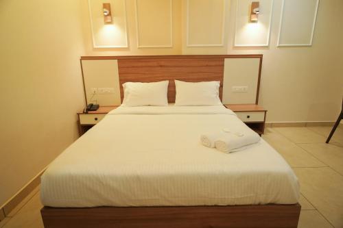 a bedroom with a large white bed with two pillows at AR Suites Kothamangalam in Kotamangalam