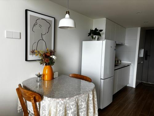a kitchen with a table and a white refrigerator at Chengdu Homestay Na's House in Chengdu