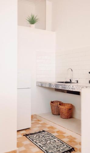 a kitchen with white walls and a counter with baskets at Tasga Guest House in Tamraght Oufella