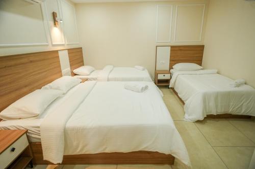 three beds in a room with white sheets at AR Suites Kothamangalam in Kotamangalam