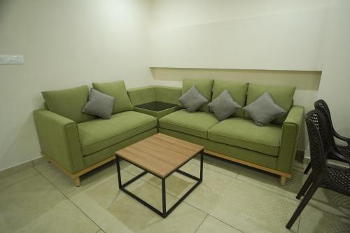 a living room with a green couch and a table at AR Suites Kothamangalam in Kotamangalam
