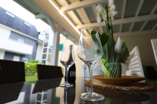 two wine glasses on a table with a vase of flowers at RESIDENCE LA TORRE appartamento FLOWER free parking in Padova