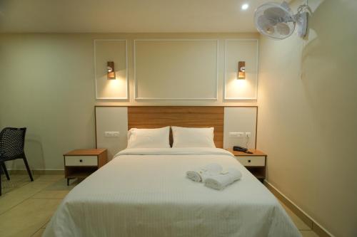 a bedroom with a bed with two towels on it at AR Suites Kothamangalam in Kotamangalam