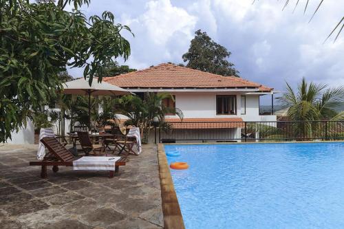 a villa with a swimming pool with a table and chairs at 5 Tropical Woods 4 BR VillaGoa Pool Cook in Bardez