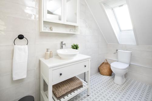 a white bathroom with a sink and a toilet at Aquilo Apartmanok in Tihany