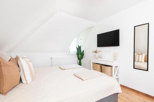 a white bedroom with a bed and a mirror at Aquilo Apartmanok in Tihany