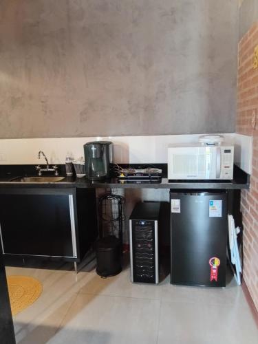 a kitchen with a sink and a microwave and a stove at Vinhedos da Serra com Ar quente e frio até 5 pessoas in Espirito Santo Do Pinhal