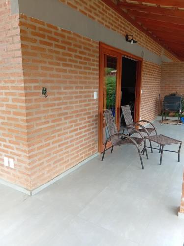 a patio with two chairs and a table on a brick wall at Vinhedos da Serra com Ar quente e frio até 5 pessoas in Espirito Santo Do Pinhal