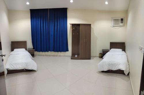 a hospital room with two beds and a blue curtain at قصر الجادل للشقق المخدومة in Ahad Rafidah