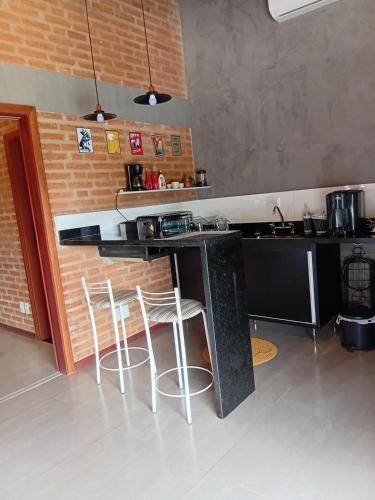a kitchen with a counter and two stools at Vinhedos da Serra com Ar quente e frio até 5 pessoas in Espirito Santo Do Pinhal