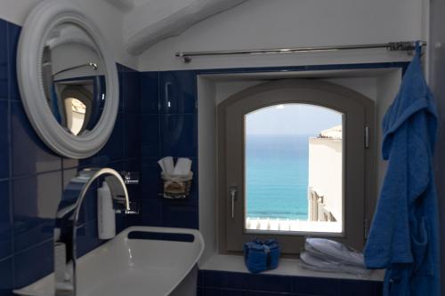 a bathroom with a mirror and a sink and a window at CasaForno1638 in Tropea