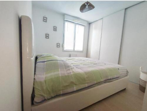 un lit dans une chambre blanche avec une fenêtre dans l'établissement Charmant T3 56m2 Vetraz-Monthoux, à Vétraz-Monthoux