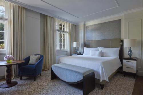 a bedroom with a large bed and a blue chair at Waldorf Astoria Amsterdam in Amsterdam