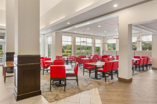 a dining room with red chairs and tables at Hilton Garden Inn Atlanta Airport North in Atlanta