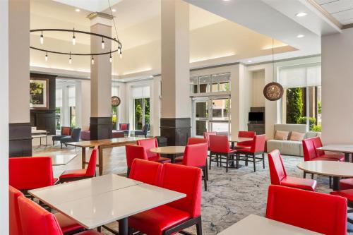 a dining room with tables and red chairs at Hilton Garden Inn Atlanta Airport North in Atlanta