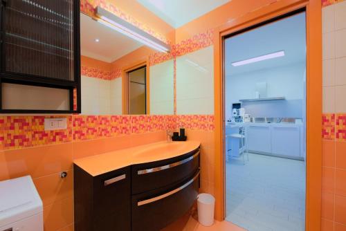 an orange bathroom with a sink and a mirror at Bilocale Luxury fronte Ospedale in Udine