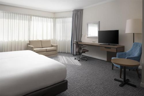 a hotel room with a bed and a desk with a computer at Hilton Paris Charles De Gaulle Airport in Roissy-en-France