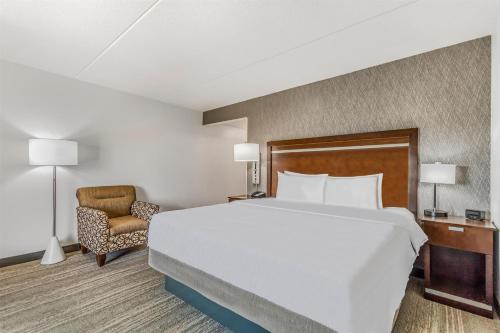 a hotel room with a large bed and a chair at Hampton Inn & Suites Detroit/Airport Romulus in Romulus