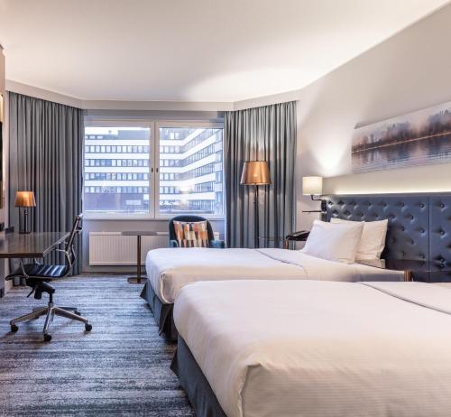 a hotel room with two beds and a desk at Hilton Helsinki Strand in Helsinki