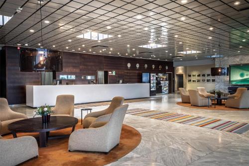 a lobby with a waiting area with chairs and tables at Hilton Helsinki Kalastajatorppa in Helsinki