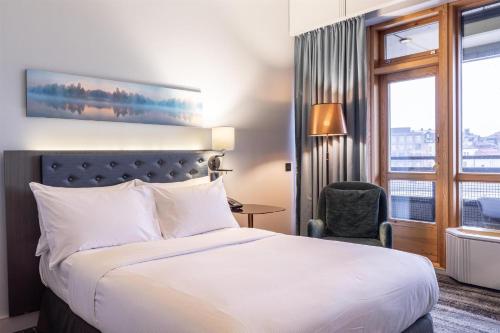 a hotel room with a bed and a chair and a window at Hilton Helsinki Strand in Helsinki