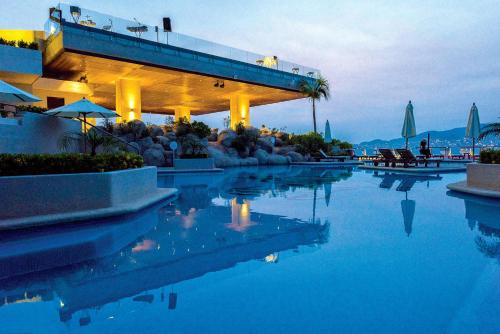 a swimming pool with blue water and a building at Las Brisas Acapulco in Acapulco