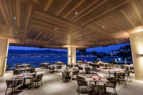a restaurant with tables and chairs and a view of the water at Las Brisas Acapulco in Acapulco