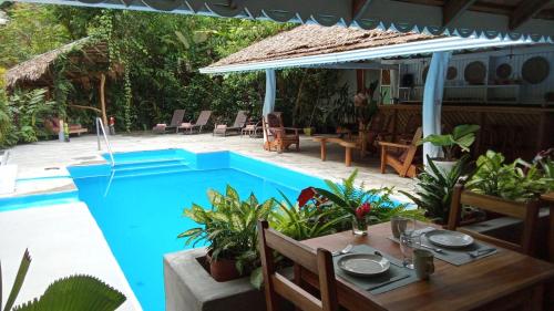 a pool with a table and chairs next to a house at La Rana De Cahuita in Cahuita