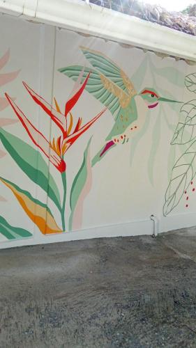 a wall with a mural of birds and flowers at La Rana De Cahuita in Cahuita