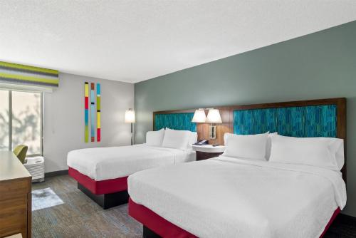 a hotel room with two beds and a desk at Hampton Inn Jacksonville Ponte Vedra in Jacksonville Beach