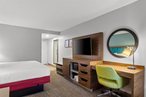 a hotel room with a bed and a desk and a mirror at Hampton Inn Jacksonville Ponte Vedra in Jacksonville Beach