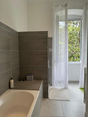 une salle de bain avec une baignoire et une fenêtre dans l'établissement côté théâtre, à Bastia