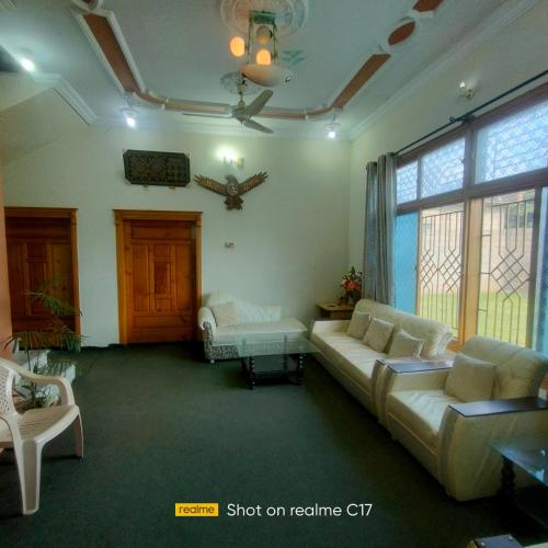 a living room with couches and a large window at Whispering Fields in Abbottābād