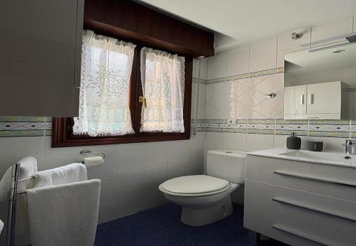 a bathroom with a toilet and a sink and a window at Mogro Las Dunas - Relax Total en Apartamento con Jardín in Miengo