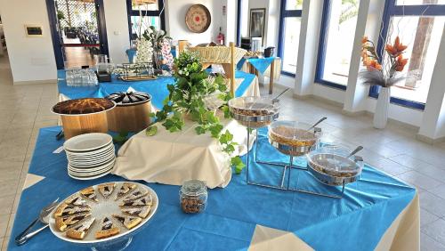 a blue table with plates and bowls of food on it at Vel Marì - Rooms on the Beach in Alghero