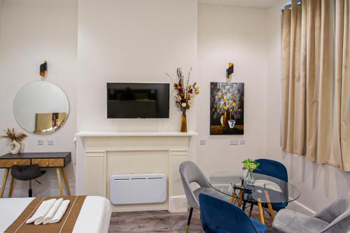 a living room with a table and a tv on a wall at Hyde Park Superior Apartments in London