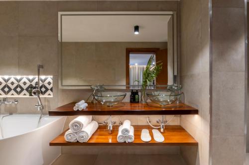 a bathroom with a sink and a tub and a mirror at Zaria Court Hotel Kigali in Kigali