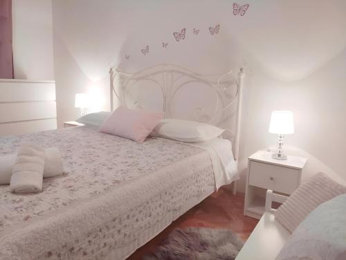 a white bedroom with a white bed with pink pillows at Siesta Apartments in Šibenik