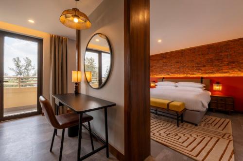 a bedroom with a bed and a desk and a mirror at Zaria Court Hotel Kigali in Kigali