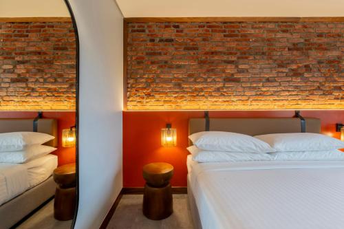 a bedroom with two beds and a brick wall at Zaria Court Hotel Kigali in Kigali