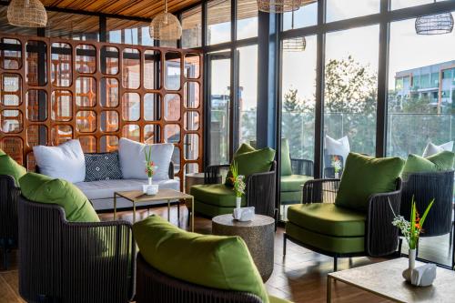 a lobby with green chairs and tables and windows at Zaria Court Hotel Kigali in Kigali