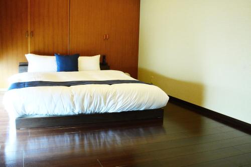 a bedroom with a bed with white sheets and blue pillows at Kototoki-Ren-501 Suite room in Hiroshima