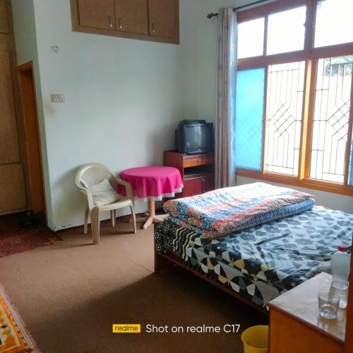 a bedroom with a bed and a table and a window at Whispering Fields in Abbottābād