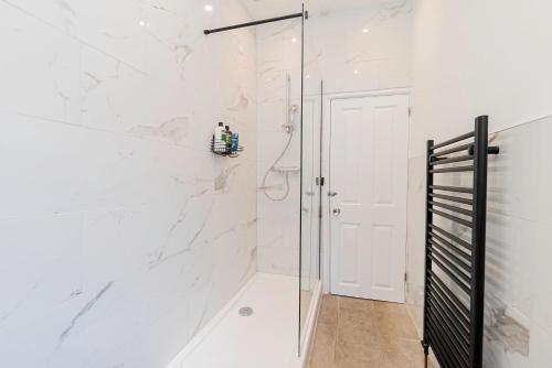 a shower with white marble walls and a glass door at Modern 5-bed - Sleeps 10-walk To Centre & Parking! in Southampton