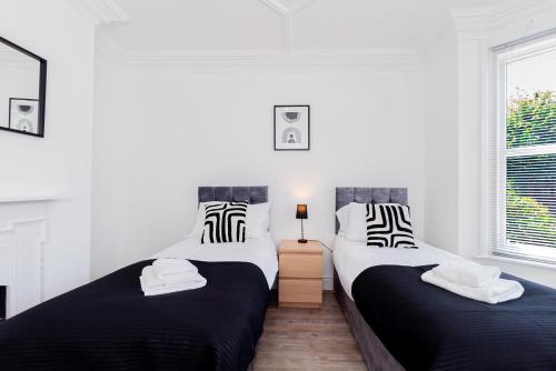 two beds in a white room with black and white pillows at Modern 5-bed - Sleeps 10-walk To Centre & Parking! in Southampton