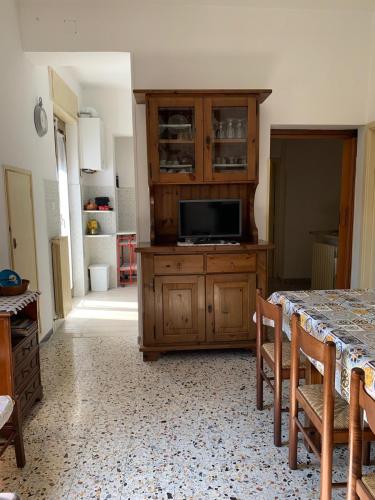 a kitchen with a table and a tv on a wooden cabinet at Tra Fiori e Antichità in Cerchiara