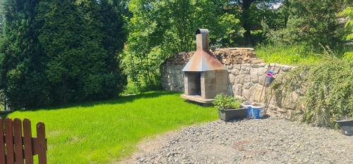 a backyard with a stone wall and a fireplace at Penzion V Kopci in Kořenov